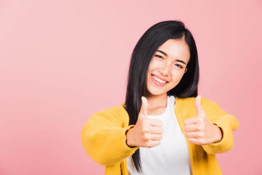 .Portrait Asian beautiful young woman smile she standing made finger thumbs up, Ok sign to agree studio shot isolated on pink background, Thai female successful like finger gesture with copy space