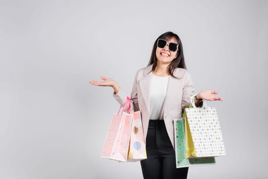 Woman with glasses confident shopper smiling holding online shopping bags colorful multicolor, Portrait excited happy Asian young female person studio shot isolated on white background, fashion sale