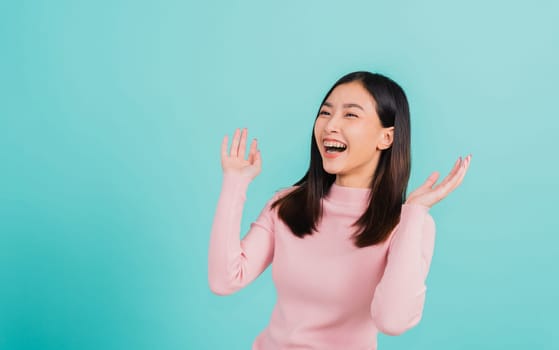 Happy young Asian beautiful woman smiling wear silicone orthodontic retainers on teeth surprised she is excited screaming and raise hand make gestures wow, studio shot isolated on blue background