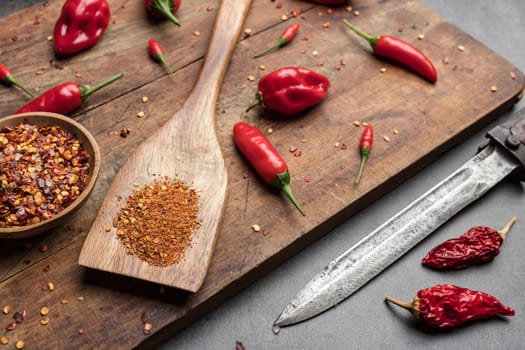 Variety of fresh and dried chili peppers on rustic background