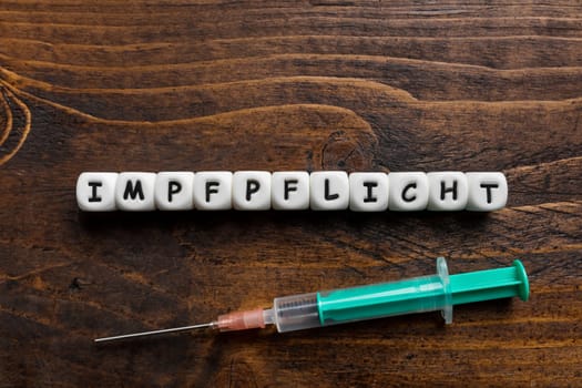 Corona virus Covid-19 vaccine text in German on wooden background