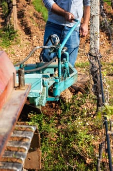 Farmer drives the plow while plowing the vineyard with the crawler tractor. Agricultural industry, winery.