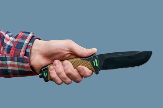 a man's hand holds a large tactical knife with a plastic handle on a gray background. High quality photo