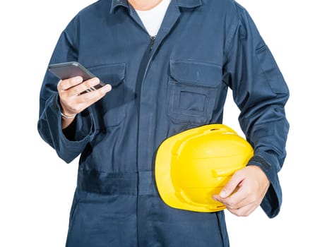 Cloes up Worker standing in blue coverall holding yellow hardhat and use smartphone isolated on white background