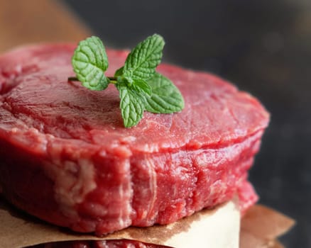 Raw beef fillet steaks on wooden board on dark background close up. Portioned filet mignons with spices and ingredients. Concept of summer food