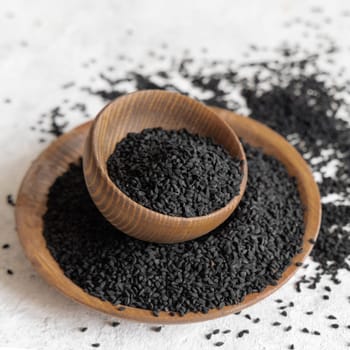 Indian spice Black cumin (nigella sativa or kalonji) seeds in wooden bowls close up. Traditional medicine, healthy and vegetarian food concept.