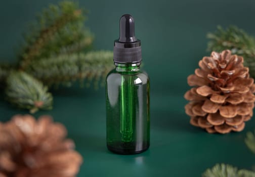 Green Pipette Dropper Bottles with blank label near fir branches and pine cones close up. Brand packaging mockup. Skincare beauty product, cream or serum. Natural cosmetics concept