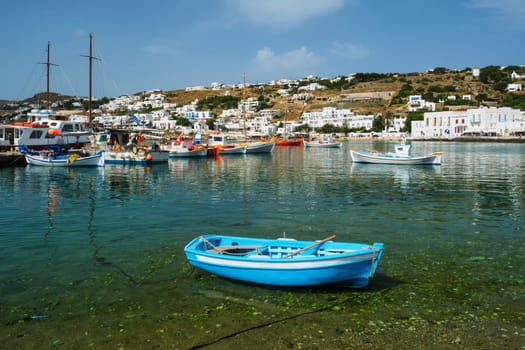 Greek fishing boat in clear sea water in port of Mykonos. Chora town, Mykonos, Greece