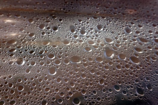 Kondenswasser-Tropfen bilden ein abstraktes Muster unter einer Plastikfolie