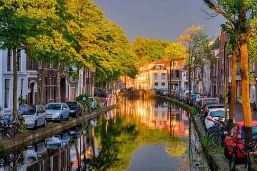 Delt canal with old houses and cars parked along on sunset. Delft, Netherlands