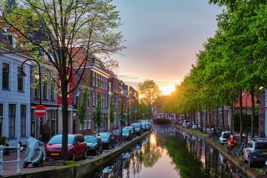 Delt canal with old houses and cars parked along on sunset. Delft, Netherlands