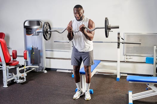 African-American man shakes biceps in the gym. High quality photo