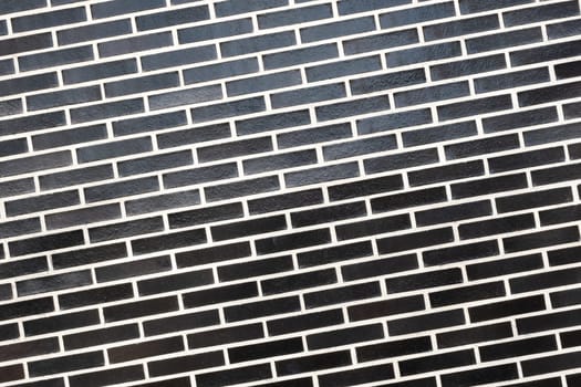 A black brick wall texture with white grout line, slanted plane. Abstract background with copy space