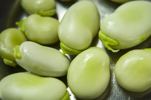 Raw green fava beans close-up on a silver board
