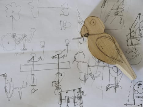 Parrot drawing with a pencil on paper and a wooden figurine of a parrot