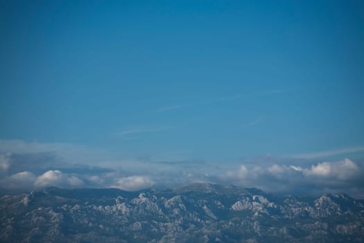 Blue skies and Velebit mountain peaks below. Copy space.