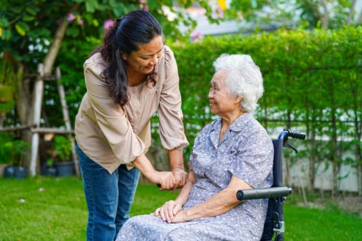 Caregiver help Asian elderly woman disability patient sitting on wheelchair in park, medical concept.