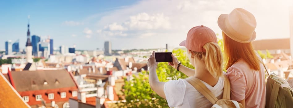 Two woman taking some photos on the phone of the Old Town of Tallinn. Concept of the tourism. Beautiful panoramic view.