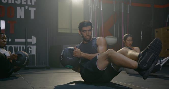 Young muscular athletic group doing training abdomen exercises working out with a medicine ball in fitness gym, strength workout healthy lifestyle sport concept