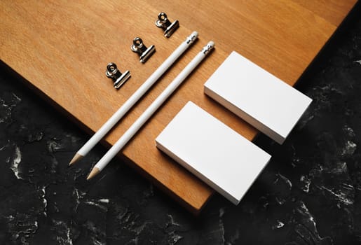 Blank branding stationery. Blank business cards, pencils and clips on wooden board background.