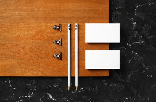Corporate id template. Blank business cards, pencils and clips on wooden board background. Flat lay.