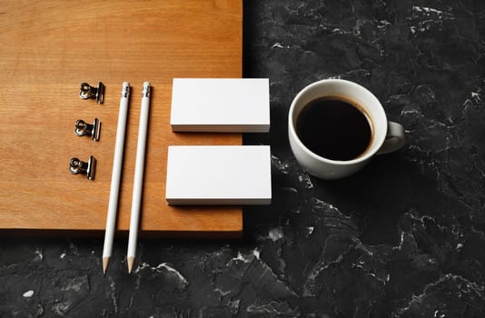 Coffee cup, blank stationery: business cards, pencils, metal clips and wooden board. Objects for placing your design.
