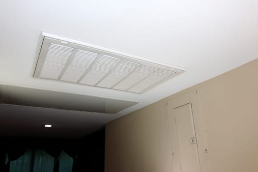 In a home ceiling indoors is a white rectangle air return vent as part of a HVAC system. Large white rectangle ceiling air return vent to a duct indoors in a home that helps to ventilate the home