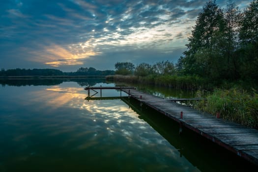 Pier over the lake and the sunset behind the clouds, Stankow, Lubelskie, Poland