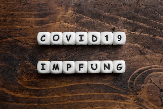 Corona virus Covid-19 vaccine text in German on wooden background