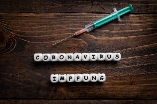 Corona virus Covid-19 vaccine text in German on wooden background