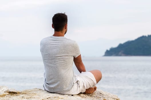 Young man sitting on the coast and meditating