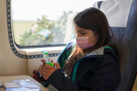 Little girl playing with water classic toy. Non-electronic entertainment for children in train