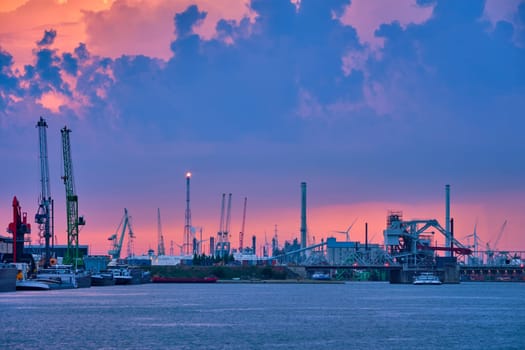 Port of Antwerp with harbor cranes in twilight and a ship passing under brigde Antwerp, Belgium