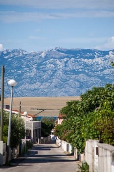 A small alley towards the sea in the apartment complex Lučica on the island of Vir, Croatia. View of the sea and the mountains.