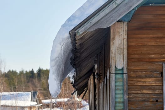 a block of ice hangs from the roof of the house. High quality photo