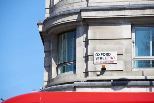Detail of Oxford Street sign next to an empty window, with ceiling of famous red bus at the bottom of the frame.