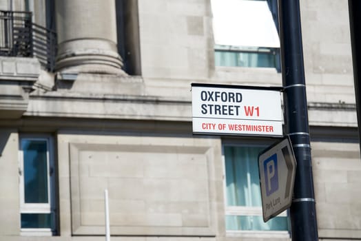 Detail of Oxford Street sign next to a parking direction arrow on pole.