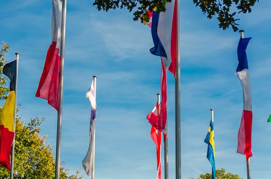 international flags blowing in the wind against a blue sky.