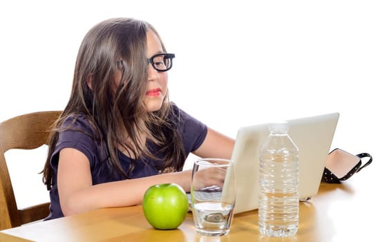 a little girl doing her homework on her computer on white