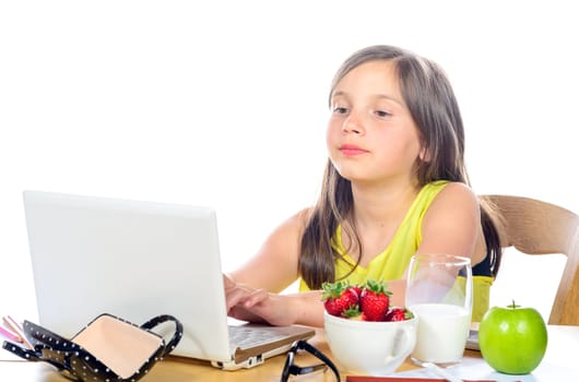 a little girl doing her homework on her computer on white