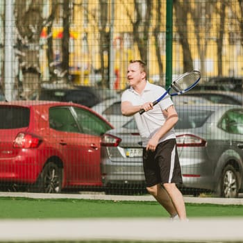 young man play tennis outdoor on tennis field at early morning