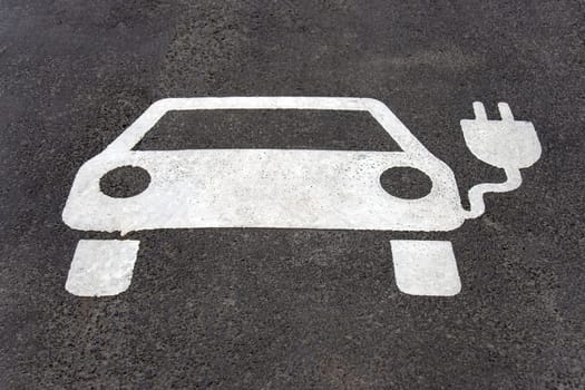 Parking space reserved for electric car. Asphalt marked with a car and plug.