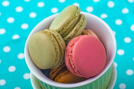 Sweet Macarons with green bowls and green fabric background
