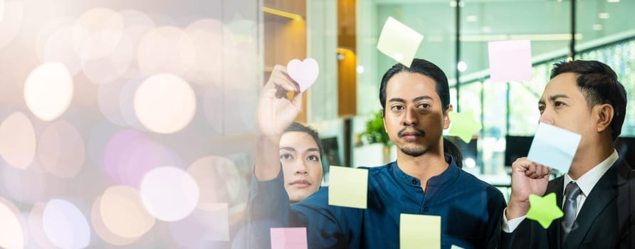 Businessman writing sticking adhesive notes on glass wall in office and team help to creative idea, Teamwork working write work stickers reminder on paper at widows, business and collaboration concept