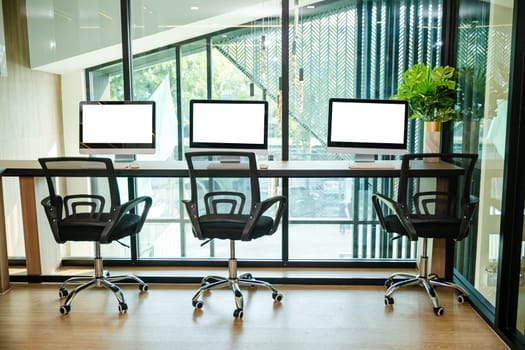 Workspace desk. Computer desktop blank screen in front of window in office, blank screen monitor on modern working desk, interior modern equipment on table