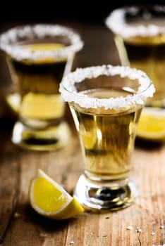 Tequila shots with salt on wooden table.