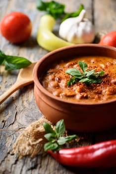 Spicy baked beans in traditional clay pot.