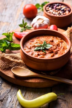 Spicy baked beans in traditional clay pot.
