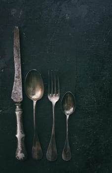 Vintage silverware on black rustic background. Retro filter.