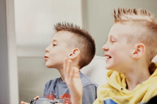 Side portrait of two laughing young boys at home enjoying playing game
